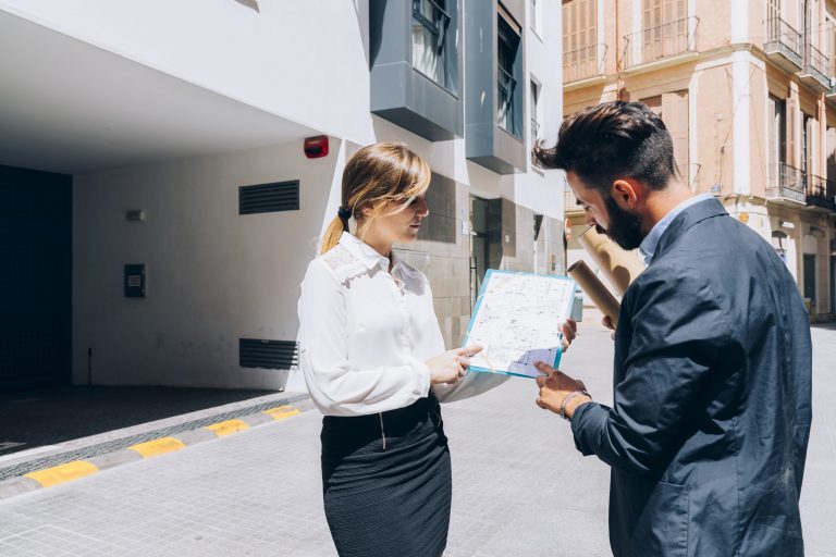 Real estate investor and architect reviewing property plans and legal documents related to entity structure and tax planning.